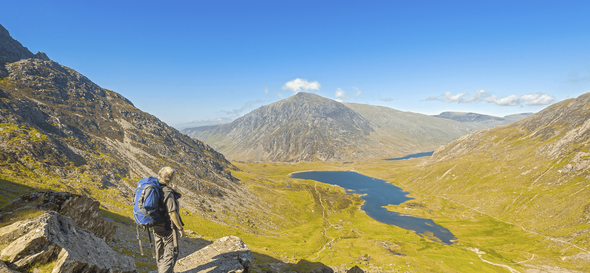 Walker on path down from devils Kitchen to Cwm Idwal with Llyn Idwal and Pen yr Ole Wen in shot